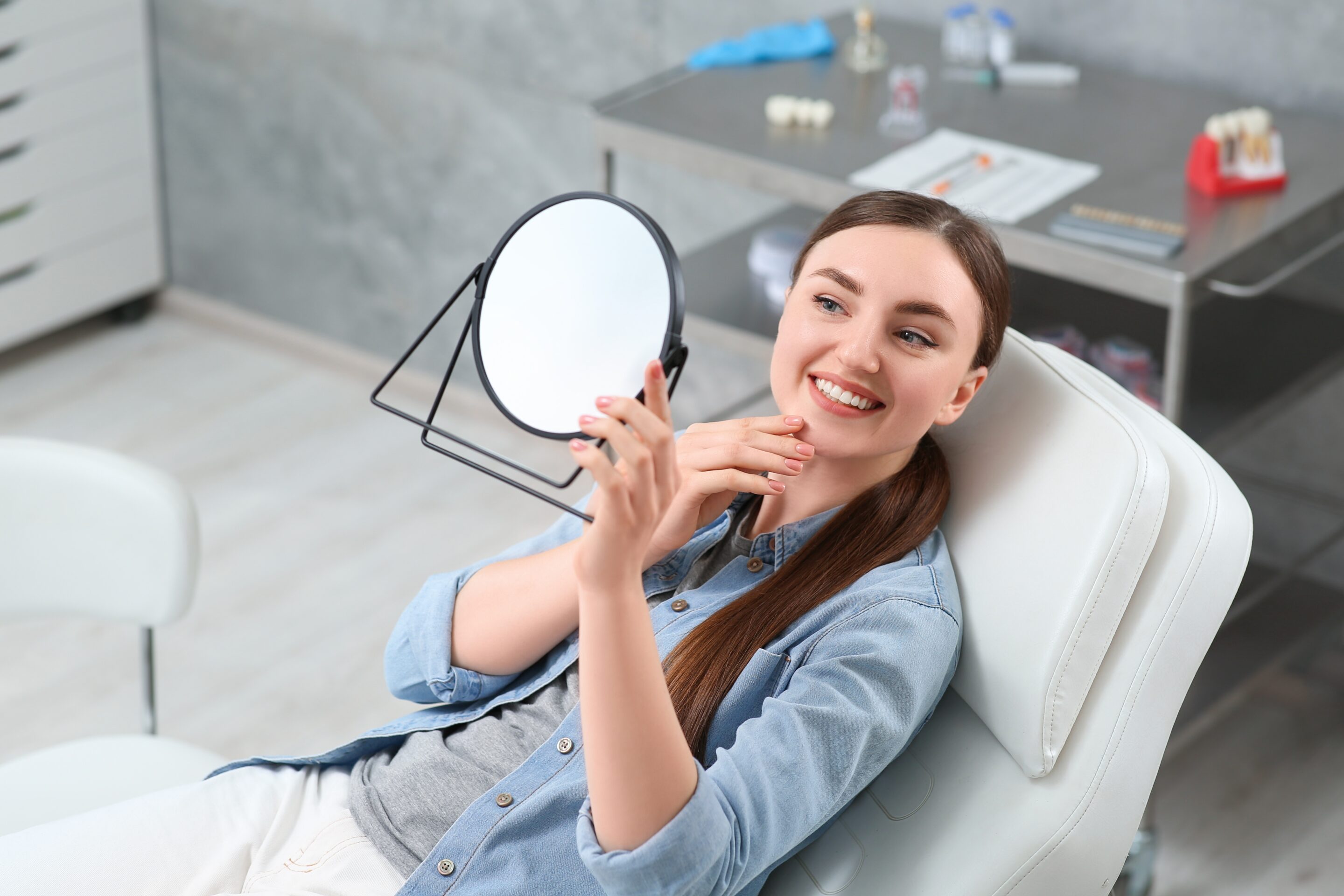 Young,Woman,Looking,At,Her,New,Dental,Implants,In,Mirror